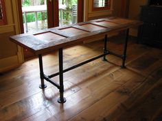 a wooden table sitting on top of a hard wood floor next to two windows with sliding glass doors