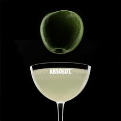 an apple falling into a martini glass with the word absolut on it