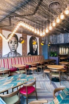 the interior of a restaurant with colorful chairs and artwork on the wall behind it,