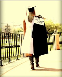 a woman in a graduation cap and gown carrying a sign