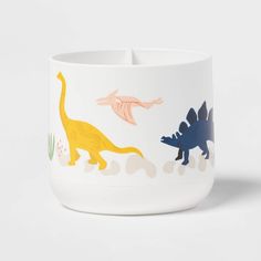 a white bowl with dinosaurs painted on it's sides and an orange dinosaur in the middle