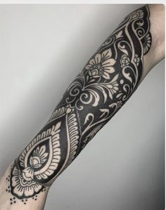 the arm is covered in black and white tattoos on it's arms, with an intricate