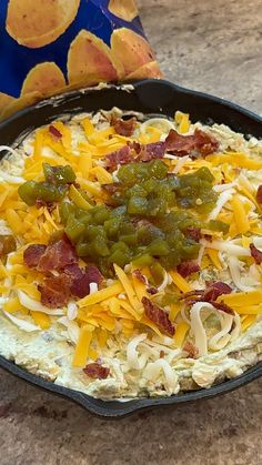 a skillet filled with cheese and toppings on top of a table next to chips