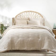 a bed with white sheets and pillows in a room next to a wicker headboard