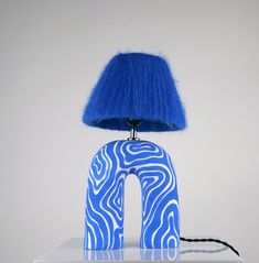 a blue lamp sitting on top of a white table next to a blue light shade