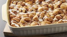 a casserole dish filled with cinnamon rolls covered in icing