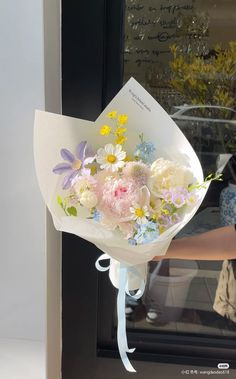 a bouquet of flowers sitting on top of a white paper wrapped around a ribbon in front of a door