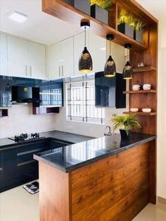 a kitchen with black and white cabinets, an island counter top and hanging lights above it