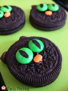 cookies decorated with green and orange candies are sitting on a green tableclothed surface