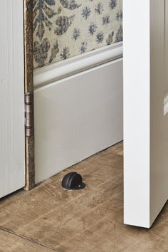 a mouse that is sitting on the floor next to a door handle and wallpaper