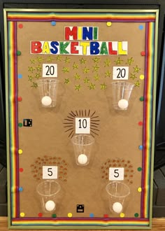 a bulletin board with cups and balls on it for numbers to be placed in front of the basket