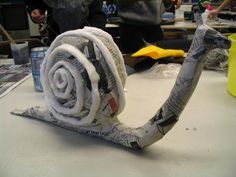 a snail made out of newspaper sitting on top of a table