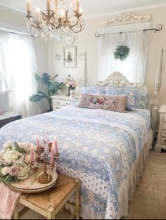 a bed sitting in a bedroom next to a table with flowers and candles on it