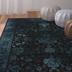 a black rug with blue and green designs on it in front of a white wall