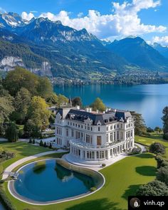an aerial view of a large white house in the middle of a lake surrounded by mountains