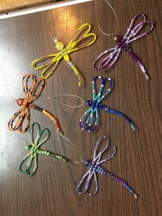 four different colored stringed dragonflies sitting on a table