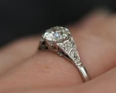 a woman's engagement ring with an old cut diamond in the center on her finger