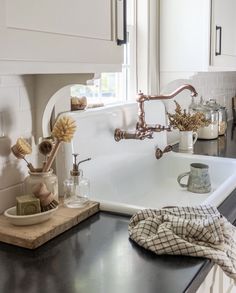 a kitchen sink sitting under a window next to a counter top with dishes on it