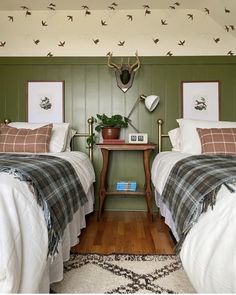 two beds in a room with green walls and wooden floors, one has a checkered blanket on the bed