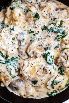 a skillet filled with mushroom and spinach covered in sauce on top of a white table