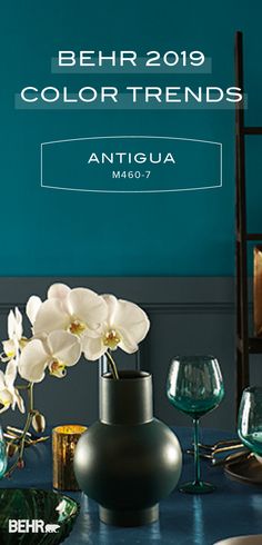 a table topped with vases filled with flowers and wine glasses next to a blue wall