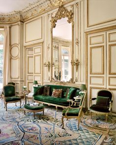 an ornate living room with green velvet couches and matching chairs in front of a large mirror