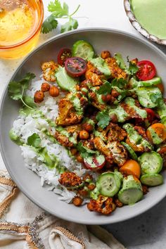 a bowl filled with rice and vegetables next to a glass of orange juice on the side