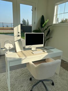 a white desk with a computer on it and a chair in front of the window