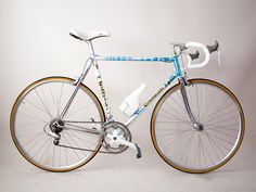 a blue and white bicycle is shown against a gray background with gold trimmings