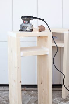 a table with a sanding machine on top of it next to a wooden shelf