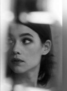 a black and white photo of a woman looking at herself in the mirror with her eyes closed