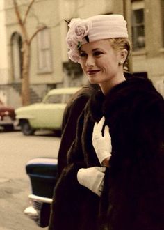 a woman in a fur coat and hat standing on the street