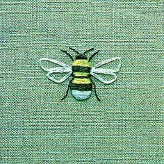 a close up of a bee on a green cloth with yellow and black stripes in the center