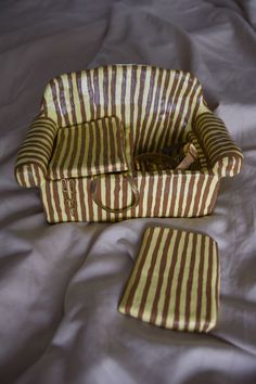 a brown and white striped bag sitting on top of a bed next to a pillow