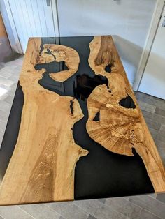 a table made out of wood and black top with an artistic design on the edge