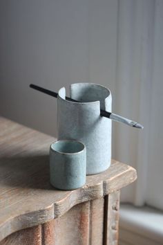 two cups sitting on top of a wooden table next to a white window sill