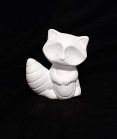 a white ceramic cat sitting on top of a black surface