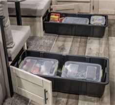 three plastic storage containers sitting on the floor next to a couch and table with food in them