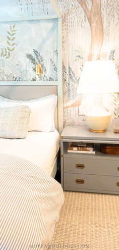 a white bed sitting next to a nightstand with a lamp on top of it