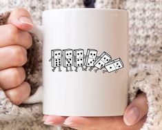 a woman holding a coffee mug with dominos on it in her left hand and two fingers