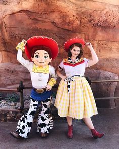 two people dressed in costumes posing for a photo next to a statue of a cowgirl and cowboy