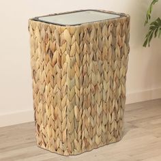 a large woven basket sitting on top of a wooden floor next to a potted plant