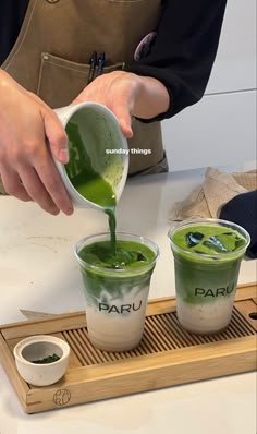 the person is pouring green liquid into their cups