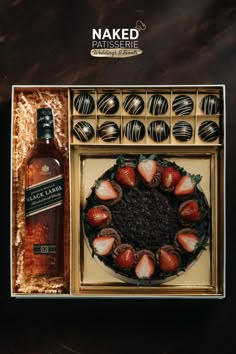 a chocolate covered cake with strawberries next to a bottle of whiskey