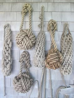 there are many ropes and knots hanging on the brick wall next to eachother