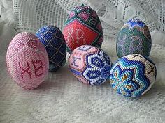 five colorful beaded eggs sitting on top of a white cloth