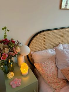 a bed with flowers and candles on it next to a night stand in front of a window