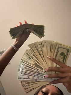 two women holding stacks of money up to their faces with one woman's hands on top of the other