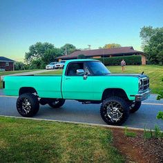 a turquoise pick up truck parked on the side of a road in front of a house