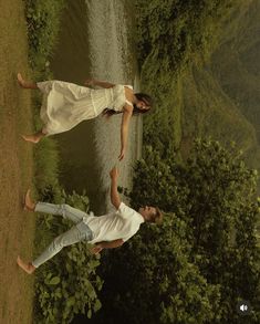 two people standing next to each other near water